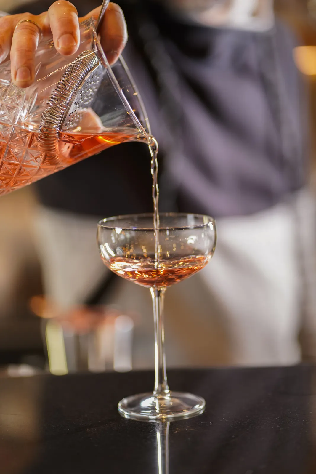 Ο bartender αδειάζει cocktail σε ποτήρι coupe