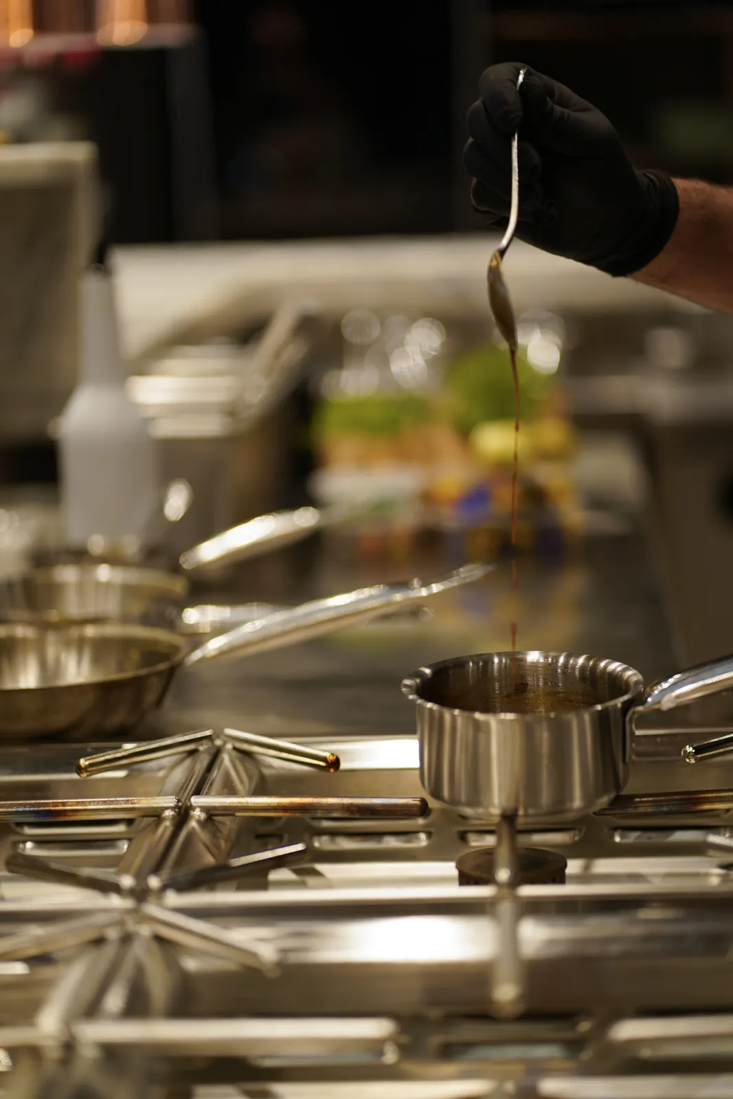 Χέρι του chef σερβίρει σάλτσα στο πέρασμα της κουζίνας